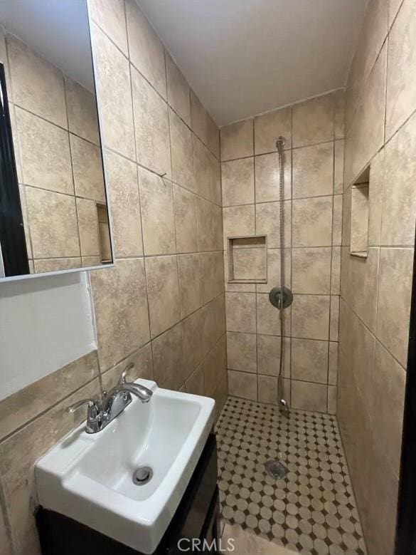 bathroom featuring a tile shower, tile walls, and sink