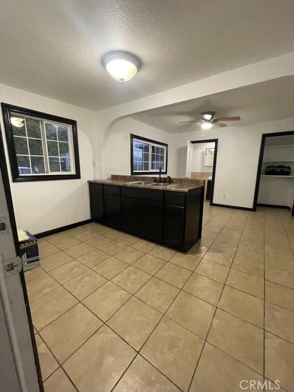 kitchen featuring sink, ceiling fan, a textured ceiling, light tile patterned flooring, and kitchen peninsula