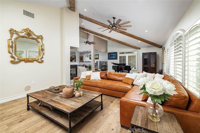 living room with a healthy amount of sunlight, beam ceiling, high vaulted ceiling, and light hardwood / wood-style flooring