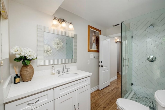 bathroom with walk in shower, toilet, vanity, and hardwood / wood-style flooring