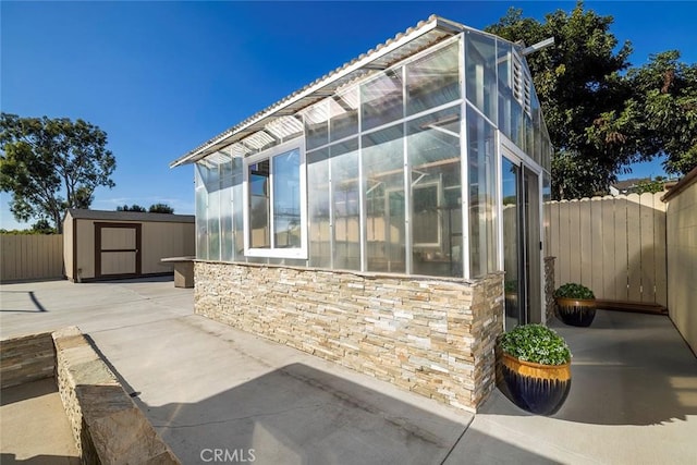 view of property exterior with a storage unit and a patio