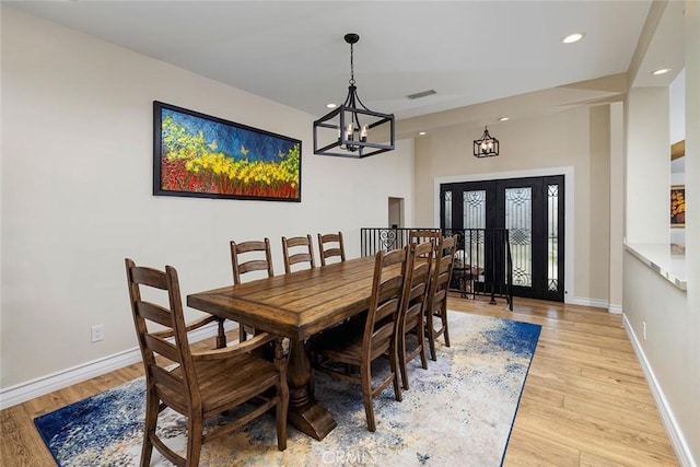 dining space with light hardwood / wood-style floors and a notable chandelier