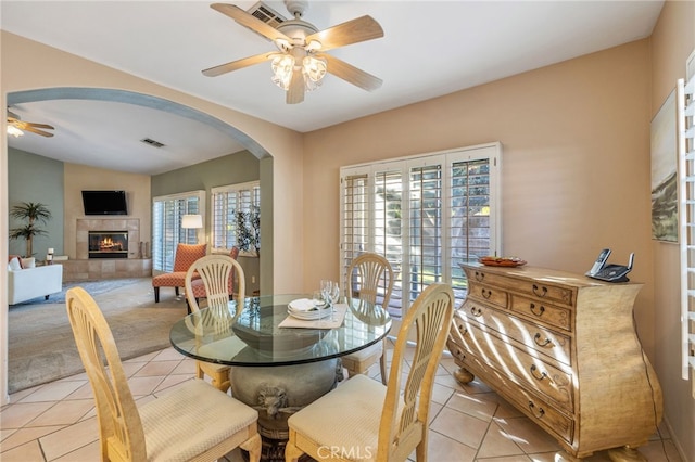 dining area featuring ceiling fan, light tile patterned flooring, and a fireplace