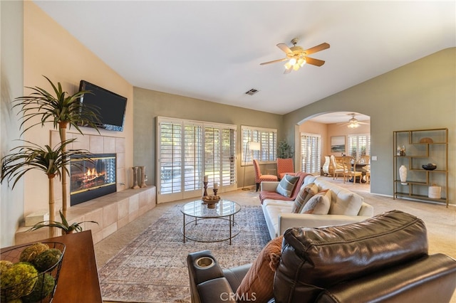 carpeted living room with a tile fireplace, ceiling fan, and lofted ceiling