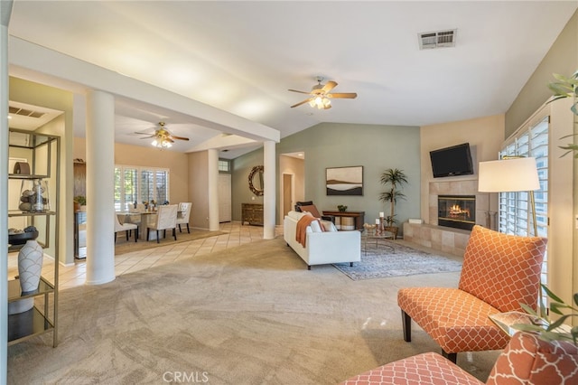 living room featuring ceiling fan, lofted ceiling, light carpet, and a tiled fireplace