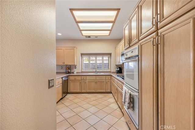 kitchen with light tile patterned floors, light brown cabinetry, sink, and appliances with stainless steel finishes