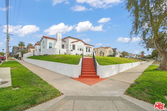 mediterranean / spanish home with a front lawn