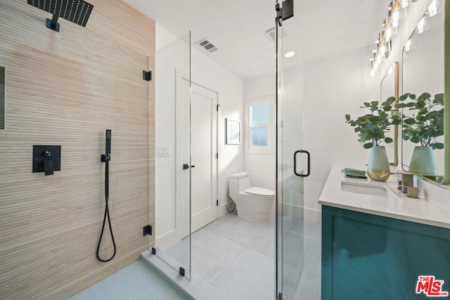 bathroom featuring toilet, vanity, tile patterned floors, and a shower with door