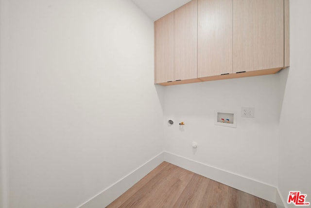 clothes washing area with gas dryer hookup, hookup for a washing machine, cabinets, and wood-type flooring