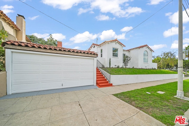 mediterranean / spanish home with a garage and a front lawn