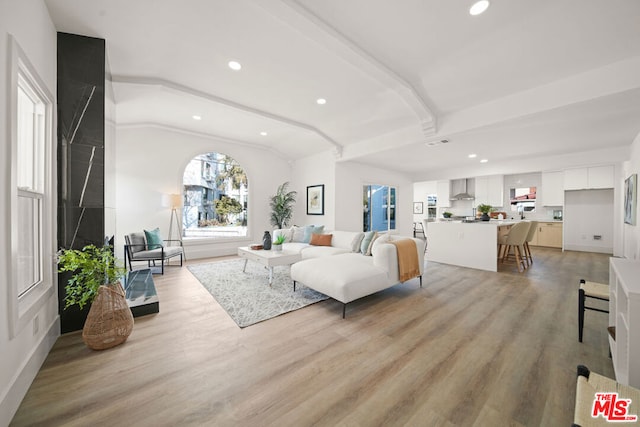 living room with vaulted ceiling with beams and light wood-type flooring