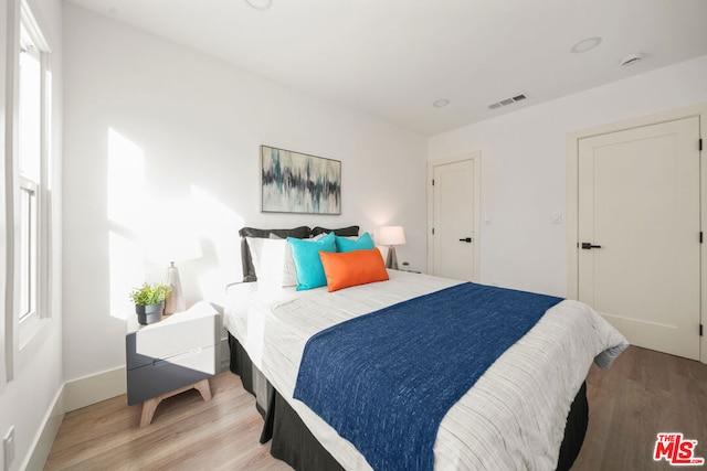 bedroom with multiple windows and light hardwood / wood-style flooring