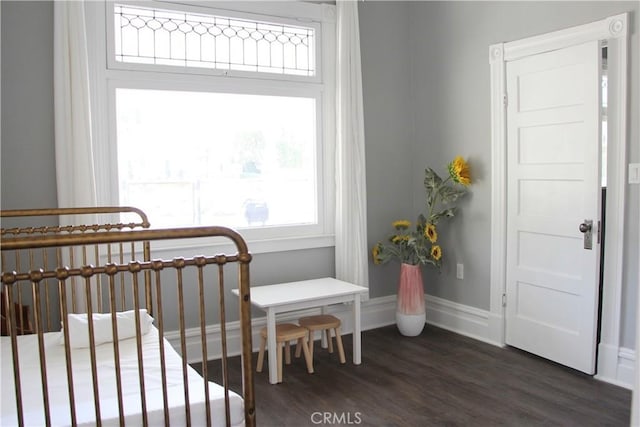 bedroom with dark hardwood / wood-style floors and a nursery area