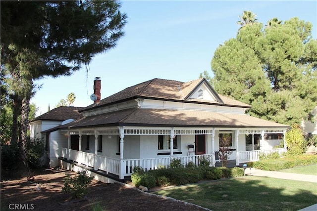 farmhouse featuring a front lawn and covered porch