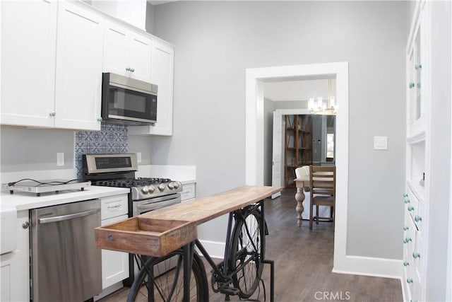 kitchen with backsplash, dark hardwood / wood-style flooring, white cabinetry, and stainless steel appliances