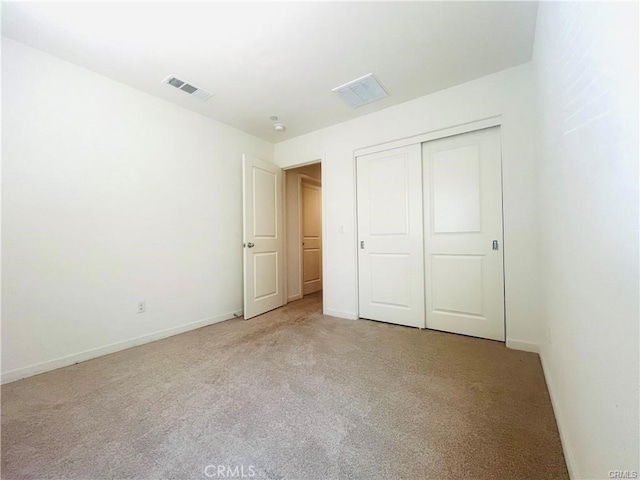 unfurnished bedroom with light colored carpet and a closet