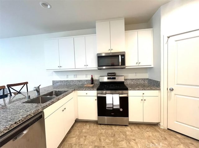 kitchen with dark stone countertops, sink, white cabinets, and appliances with stainless steel finishes