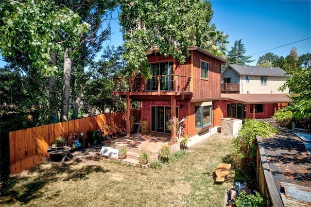 rear view of property featuring a lawn, a balcony, and a deck