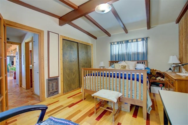 bedroom featuring ceiling fan, vaulted ceiling with beams, heating unit, light hardwood / wood-style floors, and a closet