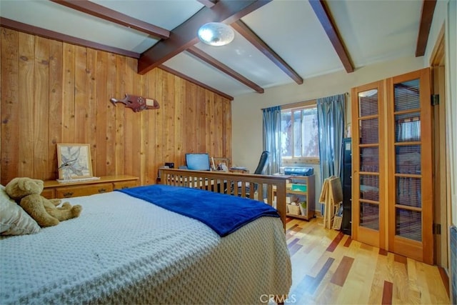 bedroom featuring vaulted ceiling with beams, light hardwood / wood-style floors, and wooden walls