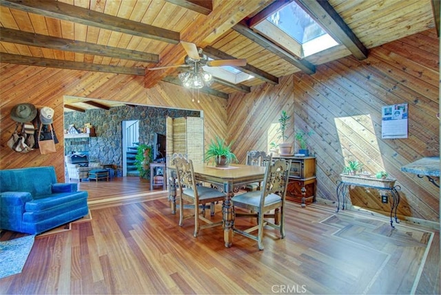 dining space with hardwood / wood-style flooring, wood walls, beamed ceiling, and a skylight