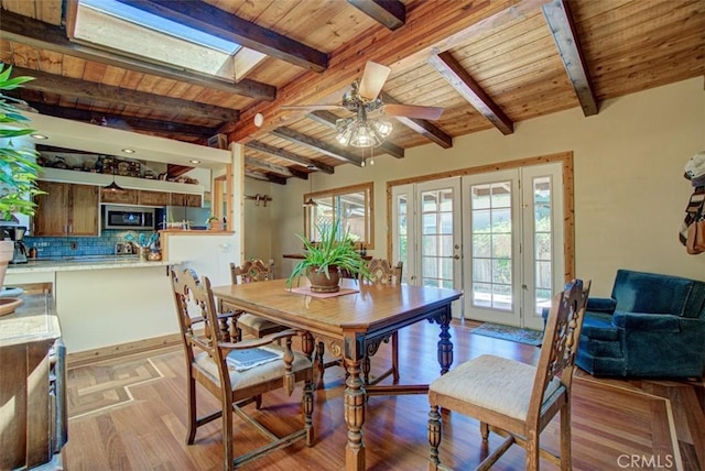 dining room featuring wood ceiling, a skylight, french doors, and a healthy amount of sunlight