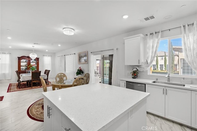 kitchen with sink, white cabinets, decorative light fixtures, and a kitchen island