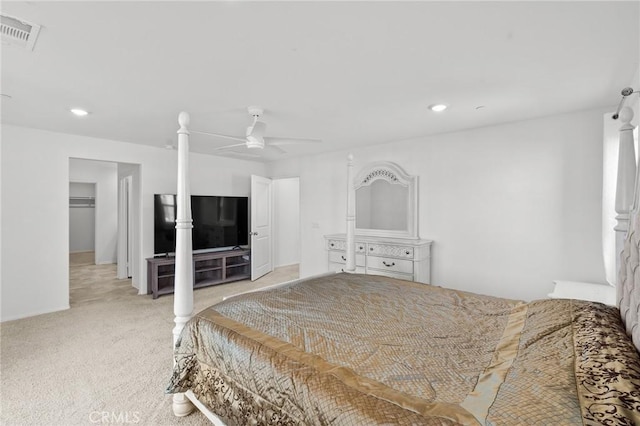 bedroom featuring ceiling fan, a walk in closet, light carpet, and a closet