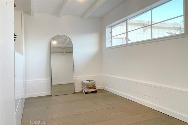 unfurnished room featuring beam ceiling and light hardwood / wood-style floors