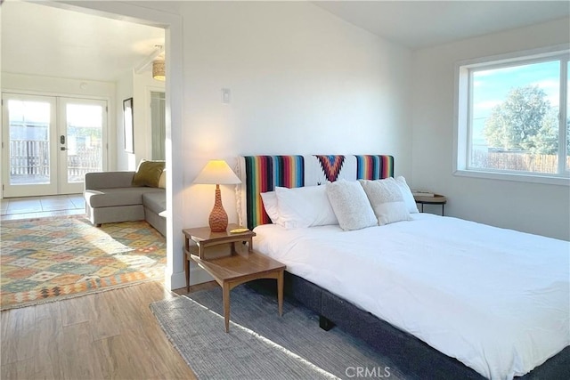 bedroom featuring light hardwood / wood-style flooring, access to exterior, multiple windows, and french doors