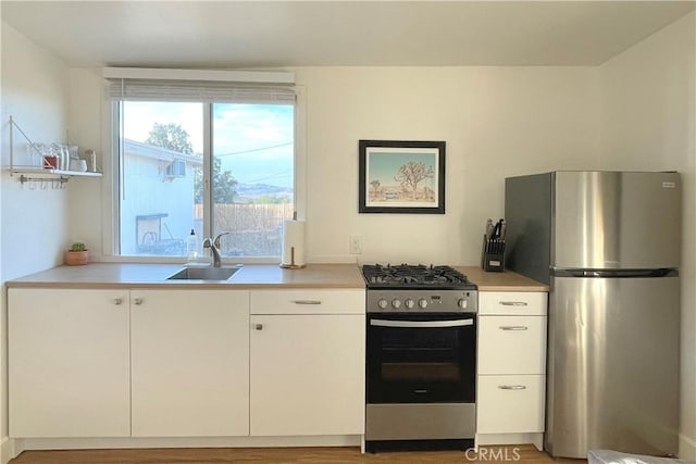 kitchen with hardwood / wood-style floors, sink, white cabinets, and stainless steel appliances