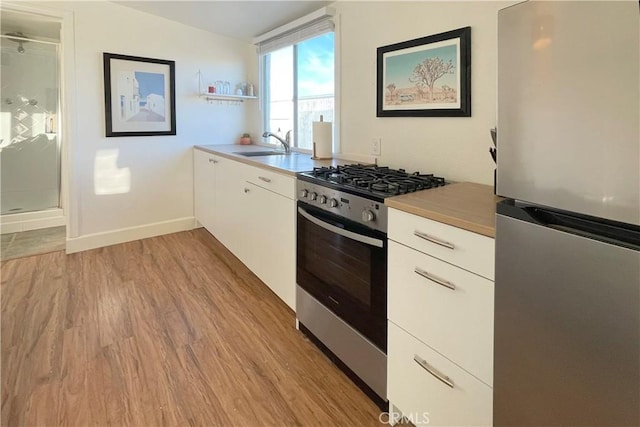 kitchen with white cabinets, sink, light wood-type flooring, and stainless steel appliances