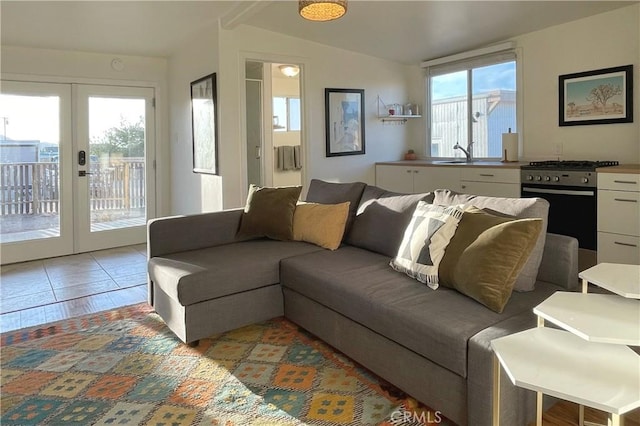 tiled living room featuring french doors, vaulted ceiling, and sink