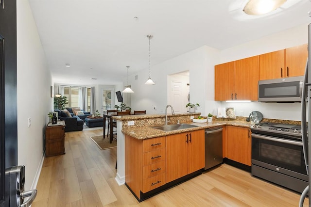 kitchen featuring kitchen peninsula, sink, light hardwood / wood-style flooring, and appliances with stainless steel finishes