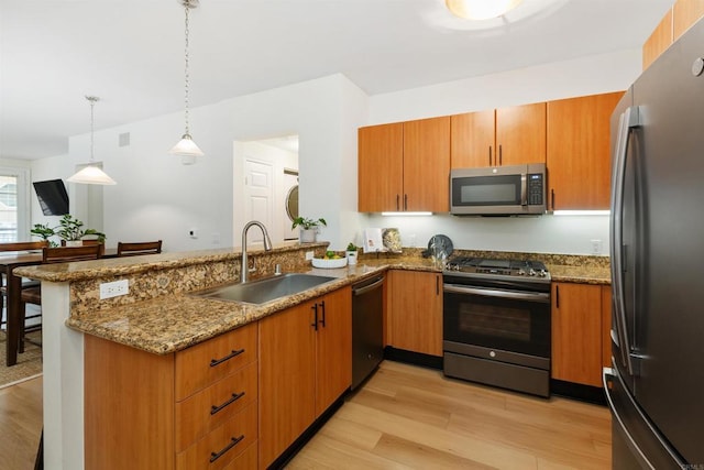 kitchen with a peninsula, dark stone countertops, appliances with stainless steel finishes, and a sink