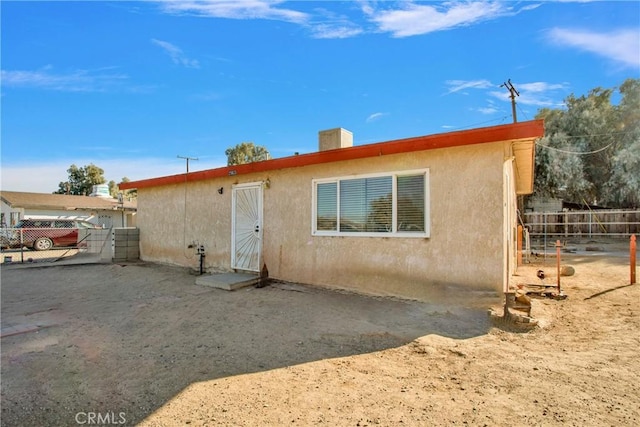 rear view of house with fence and stucco siding