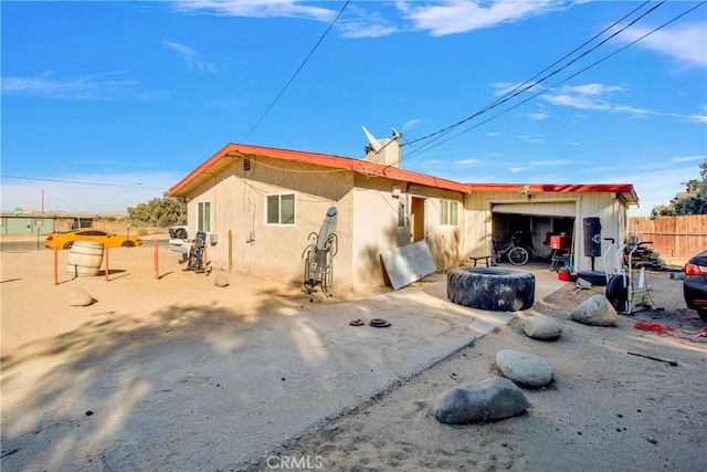 rear view of house with fence, driveway, and an attached garage