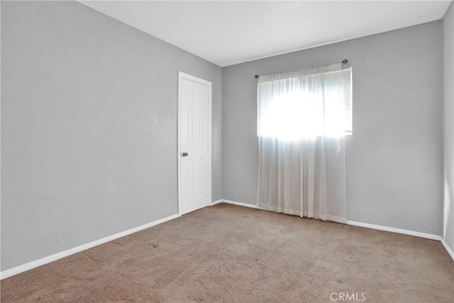 unfurnished room with light carpet and baseboards