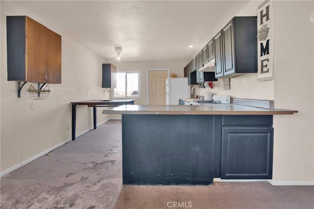 kitchen with freestanding refrigerator, light countertops, a peninsula, and baseboards