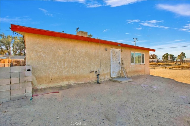 rear view of house featuring stucco siding