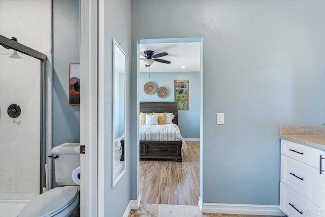 bathroom with ceiling fan, wood-type flooring, toilet, vanity, and a shower with shower door