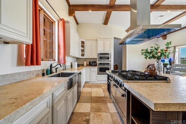 kitchen featuring sink, beamed ceiling, island range hood, white cabinets, and appliances with stainless steel finishes