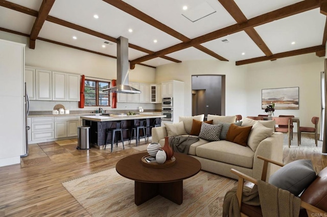 living area with visible vents, light wood-type flooring, coffered ceiling, and beam ceiling