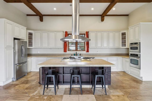 kitchen with stainless steel appliances, a breakfast bar area, beamed ceiling, and a center island