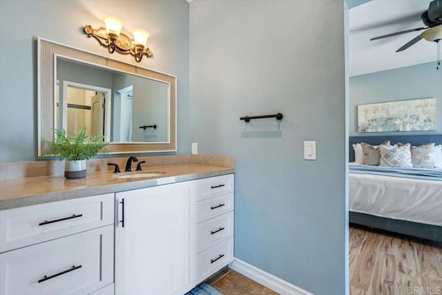 bathroom with baseboards, wood finished floors, vanity, and a ceiling fan