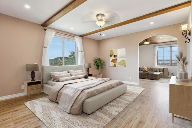 bedroom featuring arched walkways, recessed lighting, baseboards, light wood-type flooring, and beam ceiling