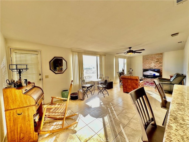 tiled living room featuring ceiling fan and a fireplace