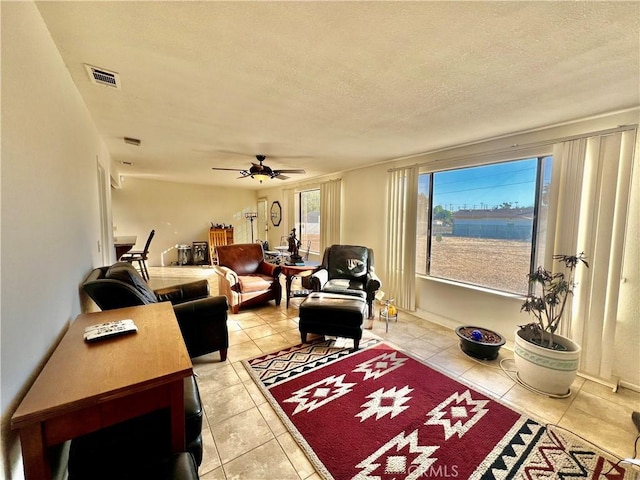 living room featuring ceiling fan, light tile patterned floors, and a textured ceiling