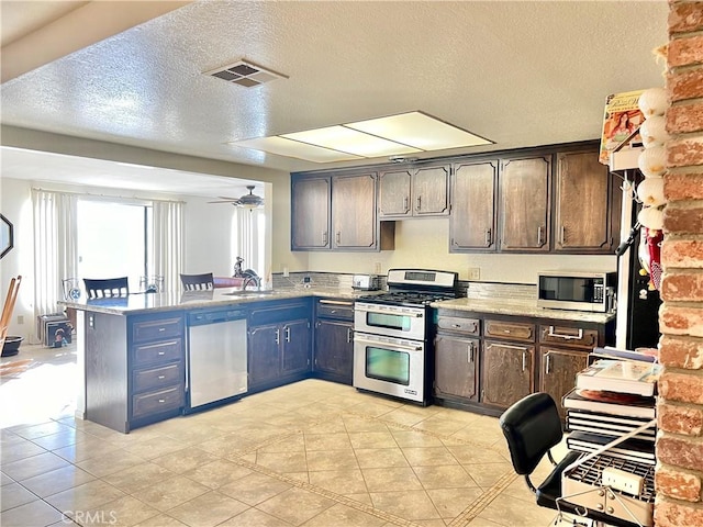 kitchen with dark brown cabinetry, ceiling fan, sink, stainless steel appliances, and kitchen peninsula