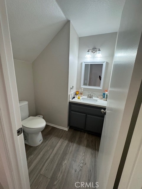 bathroom featuring hardwood / wood-style floors, vanity, toilet, and a textured ceiling